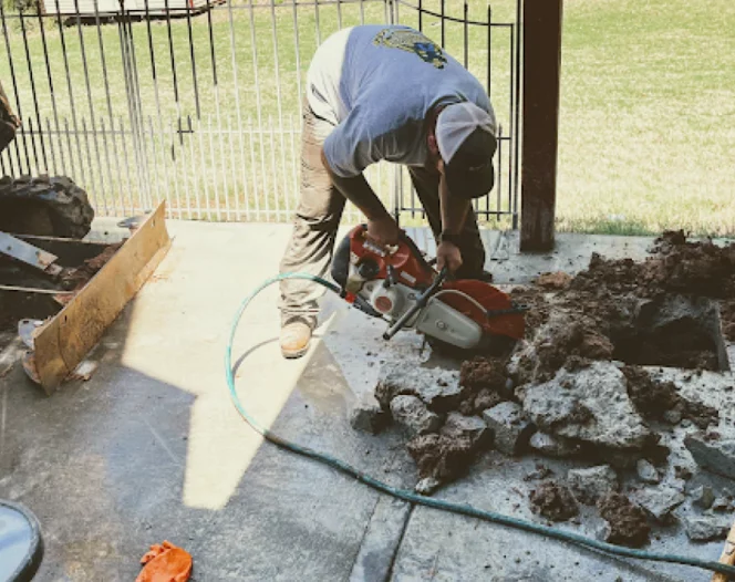 worker cutting some stones on a back yard with trees around